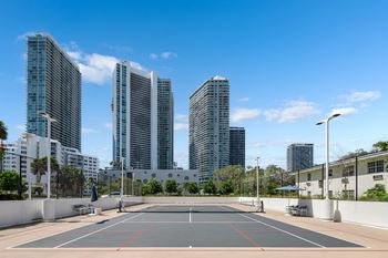 A tennis court is surrounded by tall buildings.